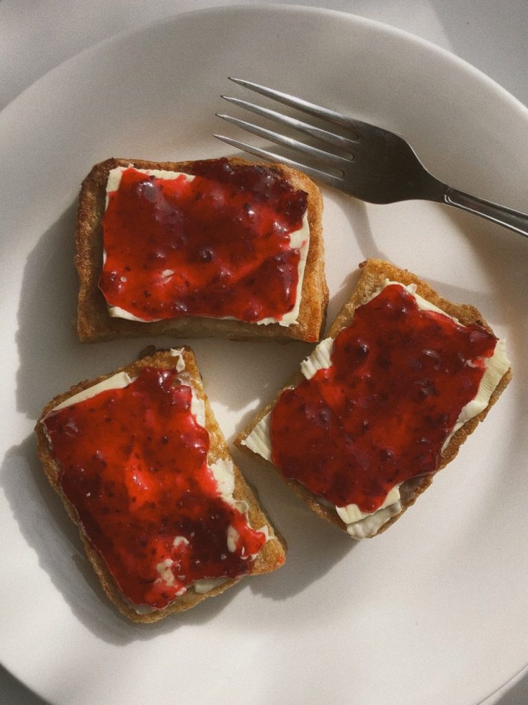 Plato de tostadas calientes con mantequilla y mermelada de fresas